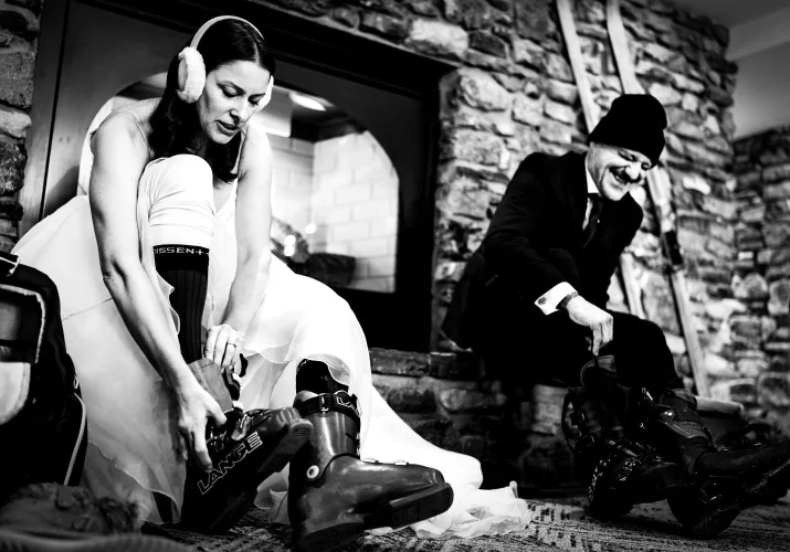 Bride and groom put skiing shoes on in Banff