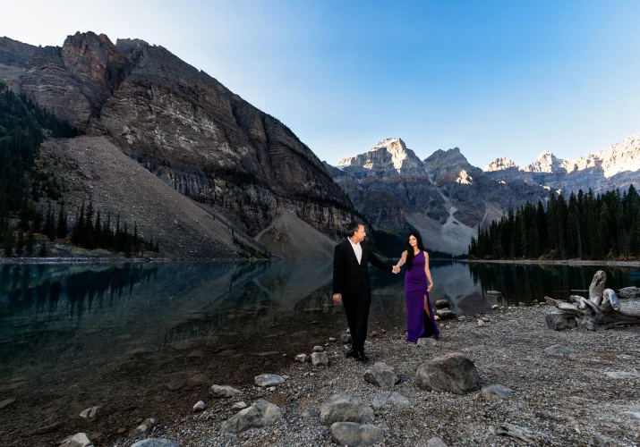 Couple in love walk at the shore of Moraine Lake and hold their hands.