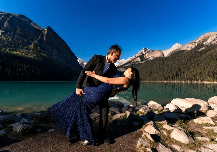 Man dips her wife during their dance at Lake Louise.
