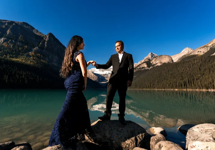 Husband leads her walking wife at the shore of Lake Louise.