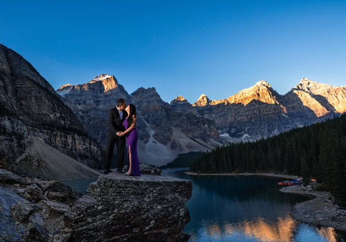 Well dressed couple standing at the rock at Moraine Lake.