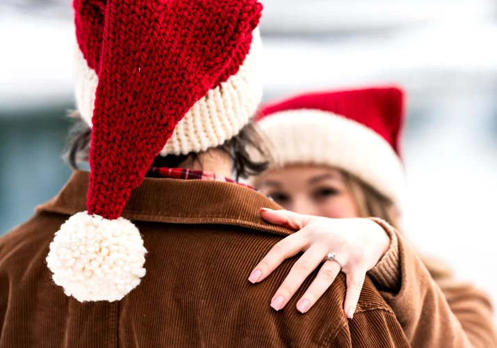 lady's hand on the man's shoulder with shinny engagement ring