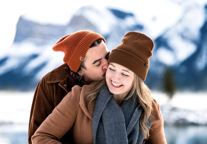 Man whispers a secret to his fiancees ear, She Laughs,