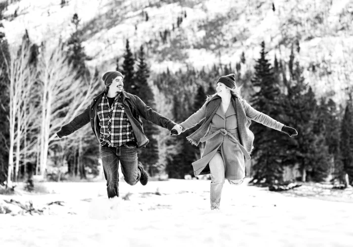 Man and lady run in a deep snow in Banff.
