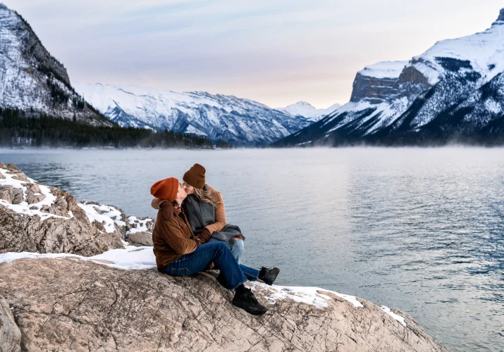 Banff Engagement Photograohy of the couple in love sitting at the shore of Minnewanka Lake.