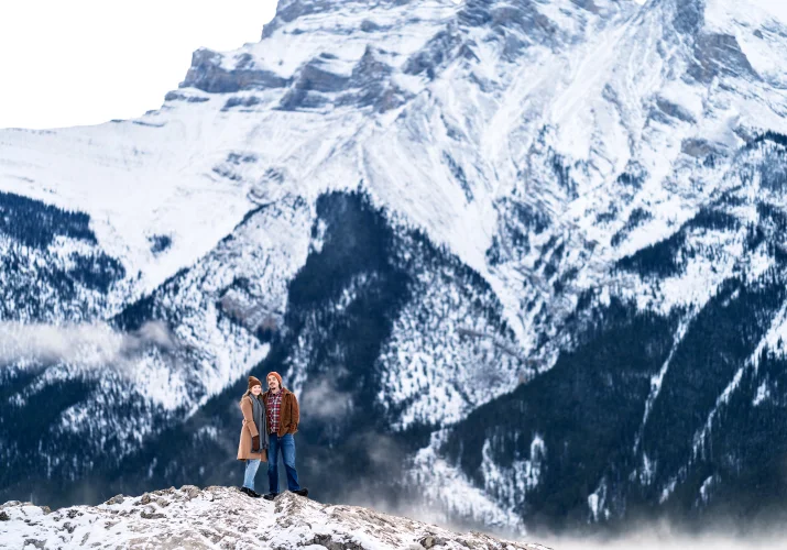 Banff Engagement Photography of the couple in a hug against a huge mountain.