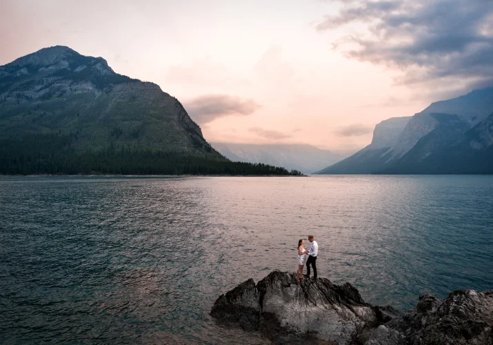 couple in love standing on the small isand at Minnewanka Lake during sunrise