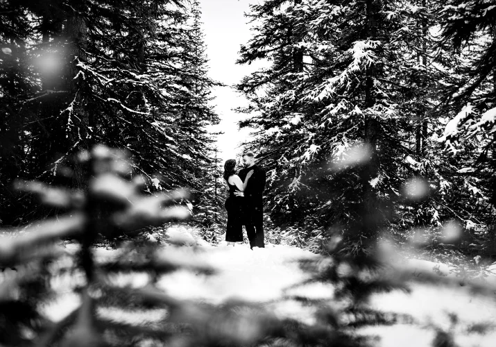 Shoot through the tree in the Banff's forest in wintertime of the couple in love.
