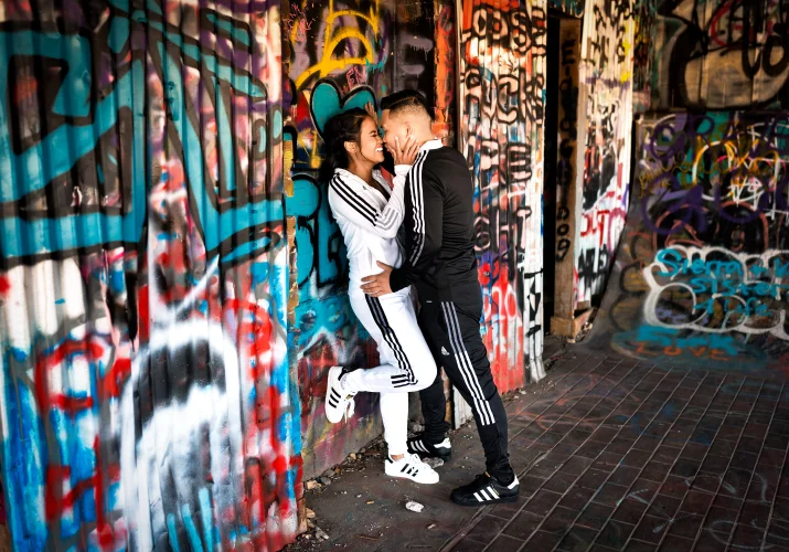 Couple in love lean over a wall an an old building with graffiti.