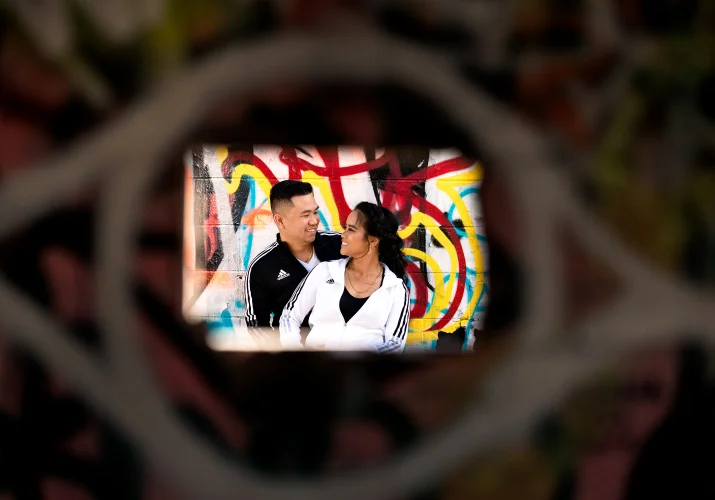Shoot through the whole in wall of the young engaged couple lookin at each other.