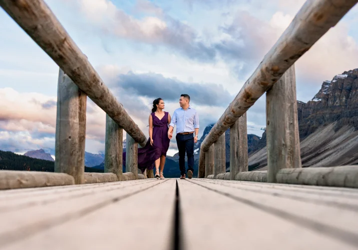 Young well dressed couple walk on the wooden bridge in the Canadian Rockies.