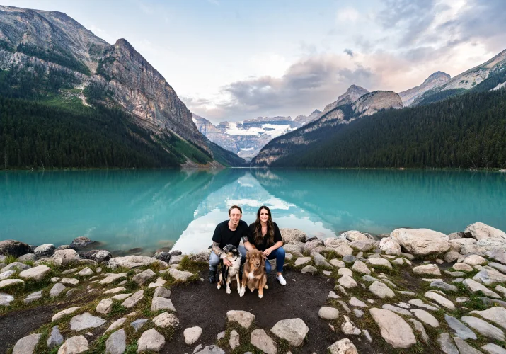 Couple and puppies in love with each other at the shore of blue Lake Louise.