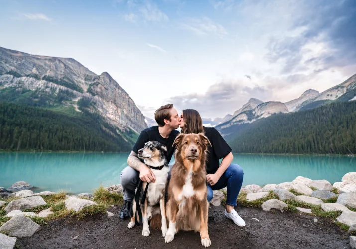 Creative Lake Louise Photography of the kissing couple in front of their cute puppies.