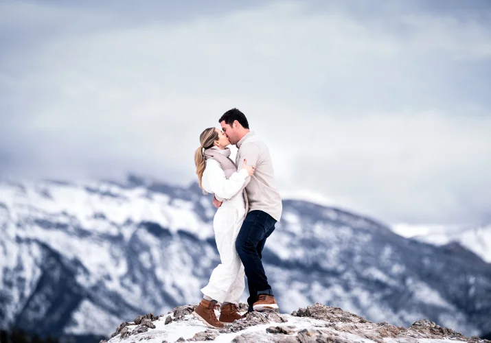 Couple in love share w kiss against Rocky Mountains