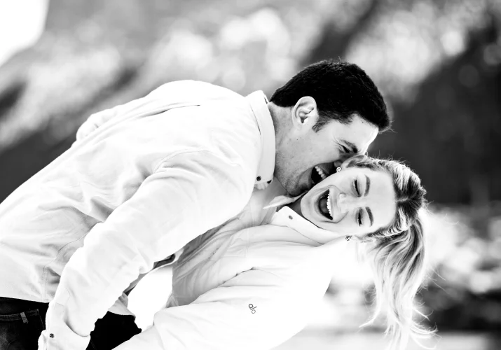 A man tries to bite his fiancees neck. She laughs.