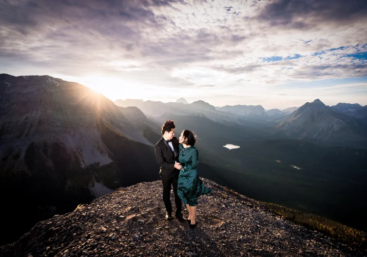 Engaged couple look at each other at the top of the mountain