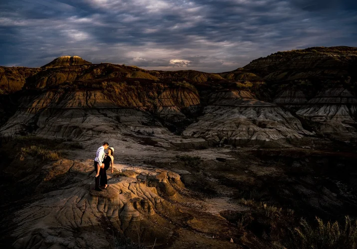 Engaged couple dancing at the stunning location Horseshoe Canyon in Drumheller. They are lighten by the sun. Moment captured by Calgary Wedding Photographer Eliza Slobodzian