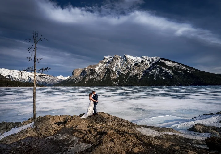 bride and groom hug during windy photo session in Banff.
