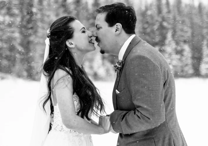 Newlyweds holding their hands and touches their noses during winter wedding in Banff National Park