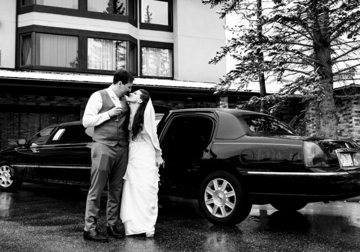 Happy bride and groom in front of the limo