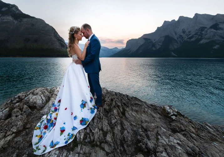 After wedding photo shoot in Banff during sunrise. Bride is wearing goregous wedding dress. Married couple look deaply into their eyes.