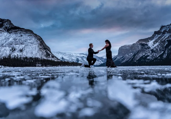 Surprise engagement at frozen Minnewanka Lake in Banff.