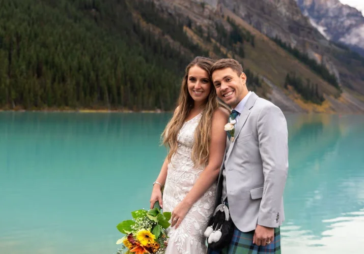 Happy bride and groom smiling at the camera during their elopement at Lake Louise.