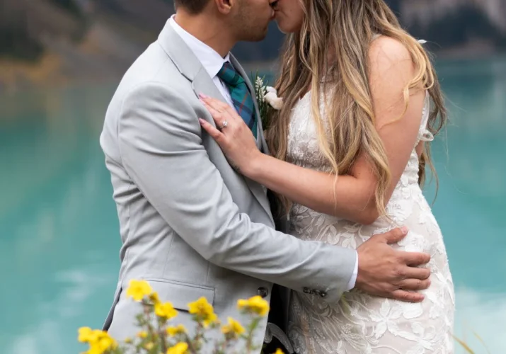 Bride and groom kissing at turquoise Lake Louise