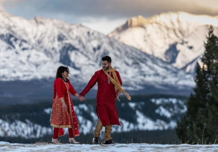 Mountain Indian Wedding. Bride and groom hold hands and walk in the Canadian Rockies.