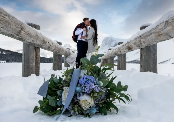 Newlyweds are kissing on the bridge after wedding ceremony in Banff.