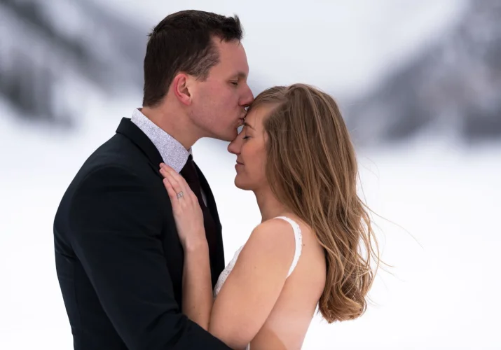 groom is kissing the bride's forehead