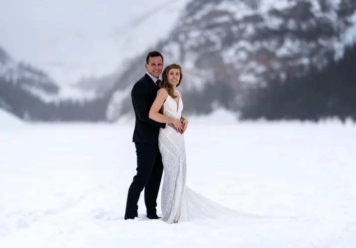 Groom hugging his new wife during wedding photo session at Lake Louise