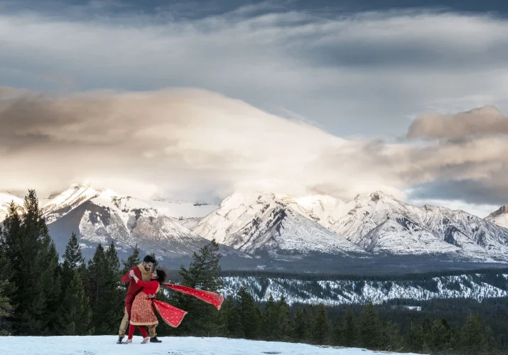 Married couple perform traditional Indian dance during their after wedding photo session in Banff.