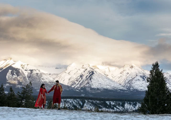 Indian wedding in Banff. Couple walking it their red indian wedding outfits in Banff.