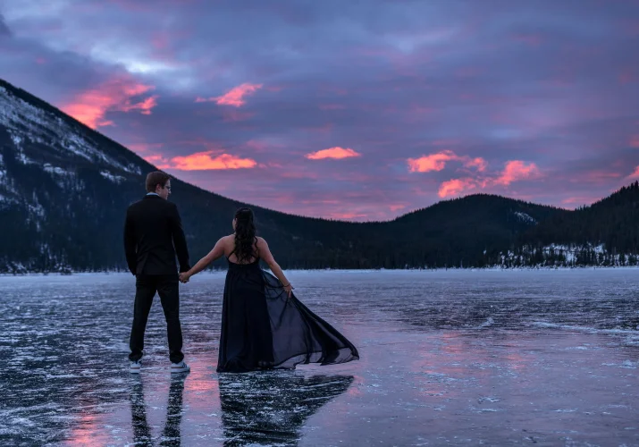 engaged couple on the frozen Minnewanka Lake during sunrise