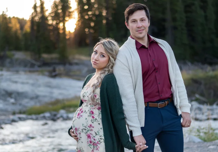 Maternity portrait in Banff. A couple celebration of their pregnancy. They smile and hold their hands.