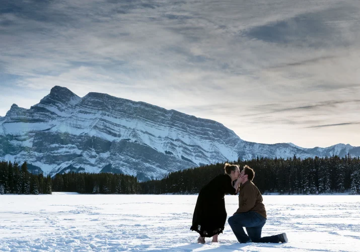 A woman is kissing his fiance after his marriage proposal in Banff.