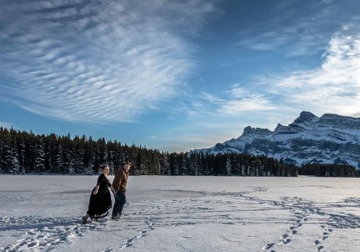 Engaged couple runs at Two Jack Lake during engagement photo session.