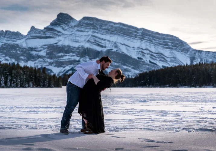 Winter engagement photo session in Banff. Engagement couple is dancing at the frozen lak.