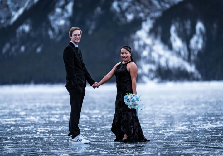 Happy couple smile at the camera during engagement photo session at Minnewanka Lake