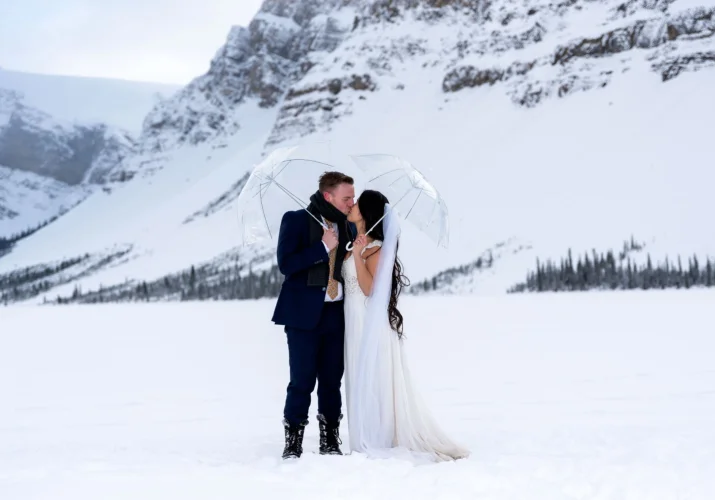Married couple kissing during winter wedding photo session at Bow Lake.