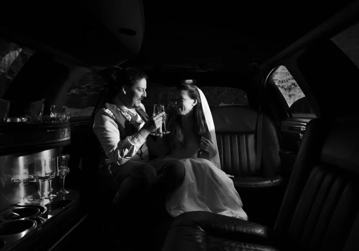 bride and groom drinking champagne in the limo