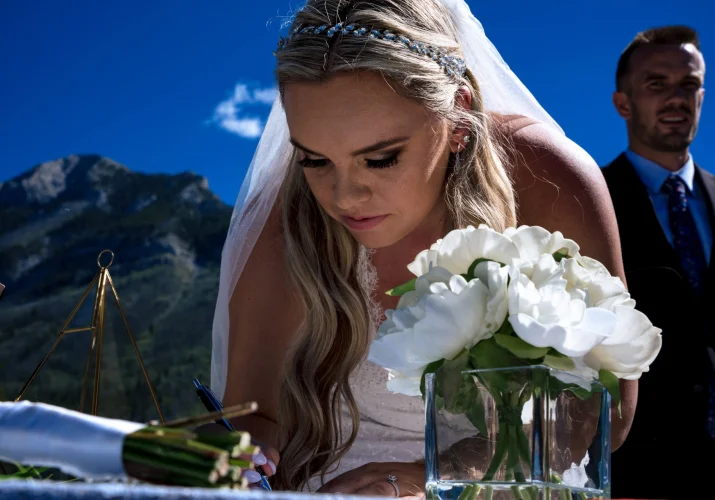 The bride signing the official paper during elopement in Banff