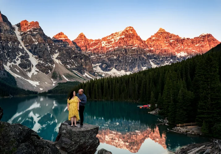 Couple standing at the rock at Moraine Lake surrounded by Rocky Mountains
