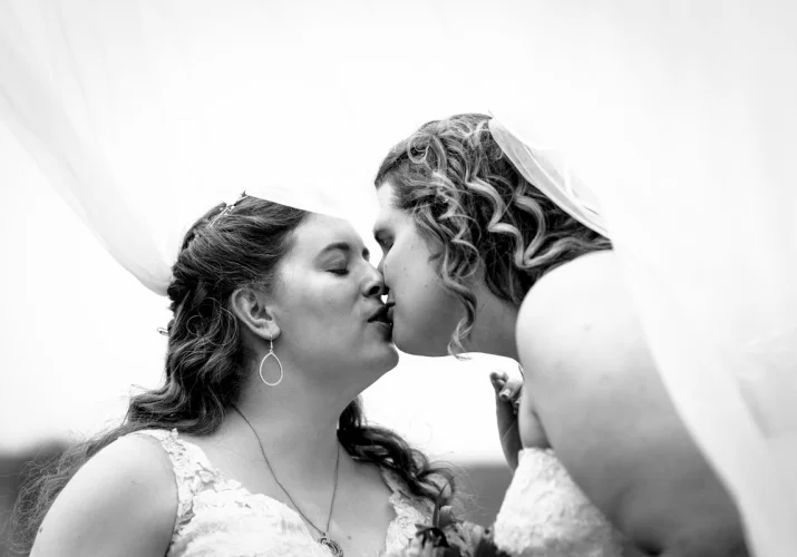 Same sec couple are kissing under the veil. Calgary Wedding Photography.