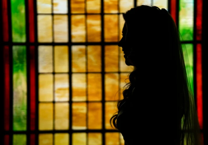 Bride's Portrait by stained glass during Calgary Wedding Ceremony in the church