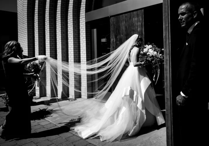 The Bride entering a church. Bridesmaids are holding her vail.