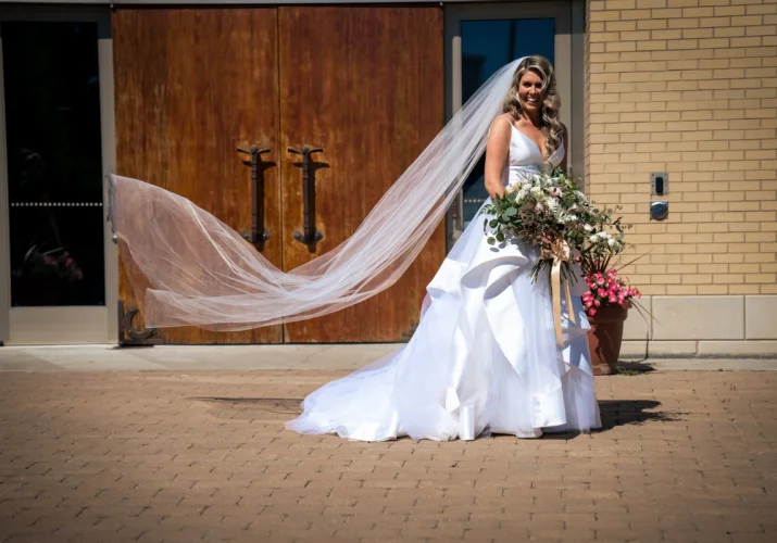 Gorgeous bride in white wedding dress is posing to be photographed by Calgary Wedding Photographers.