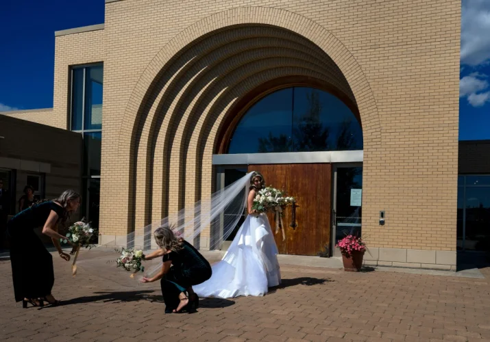 Bridesmaids are helping with the bride's vial in front of the church in Calgary.