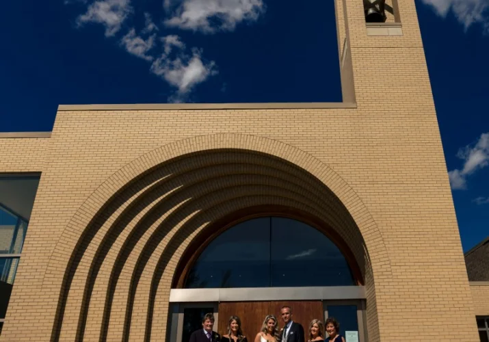 A group of the wedding quests with newlyweds are posing to Calgary Wedding Photographer in front of the church .